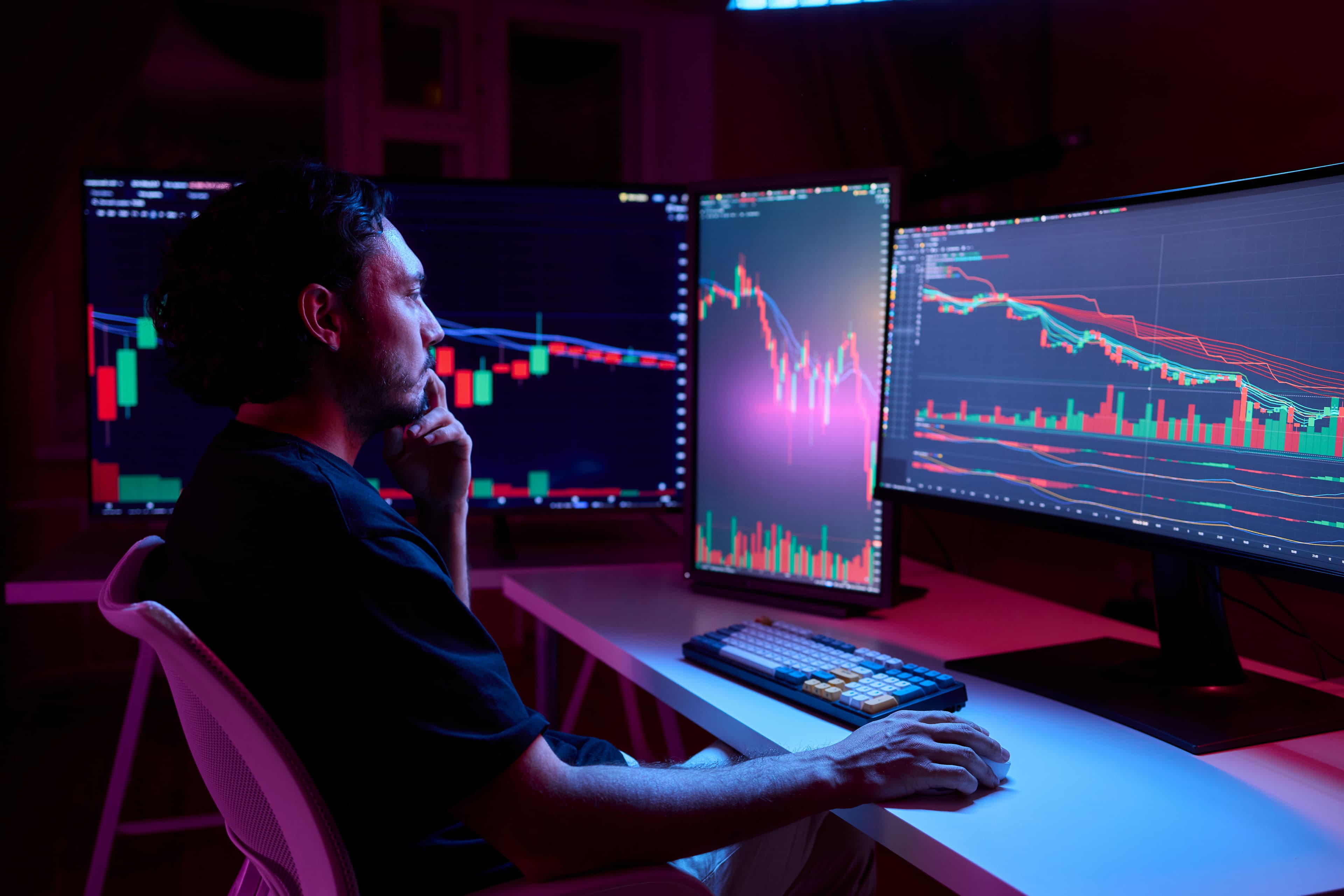 Trader con setup multi-monitor analizando tendencias del NQ en máximos históricos con alta volatilidad geopolítica