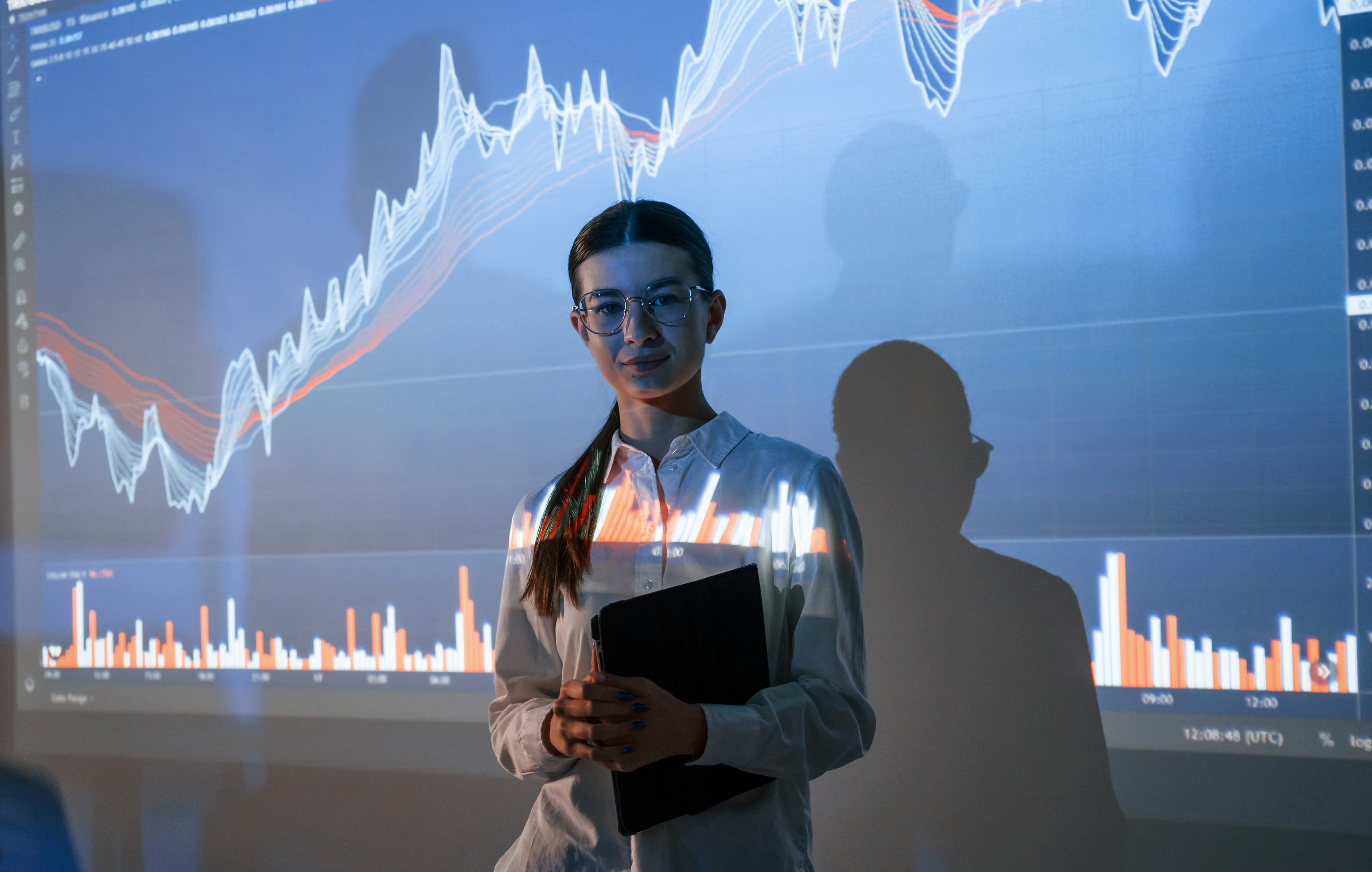 Analista frente a gráfica proyectada entendiendo cómo funciona una empresa de fondeo de futuros