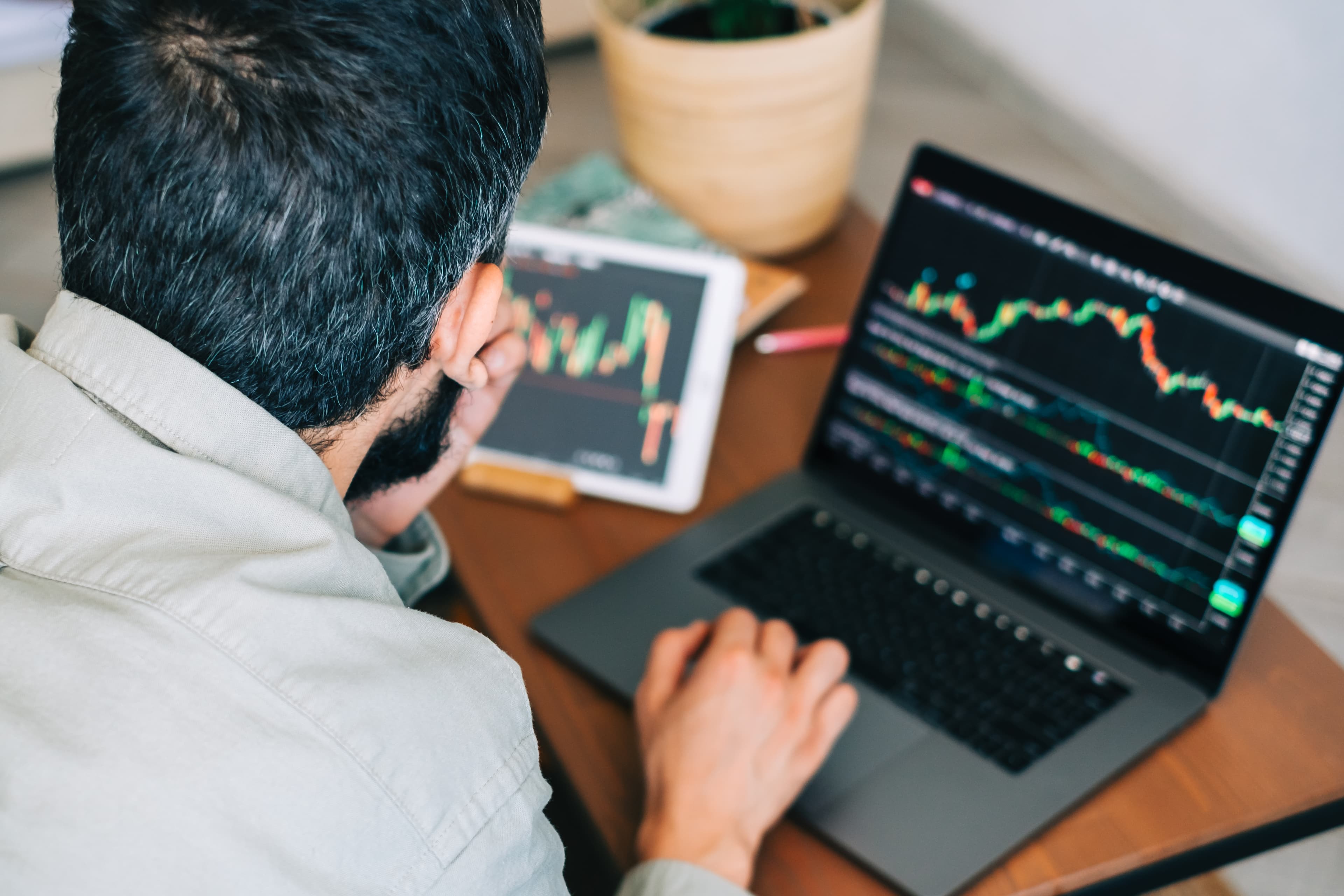 Futures trader using laptop and tablet to compare the best prop firms for funded trading in 2025