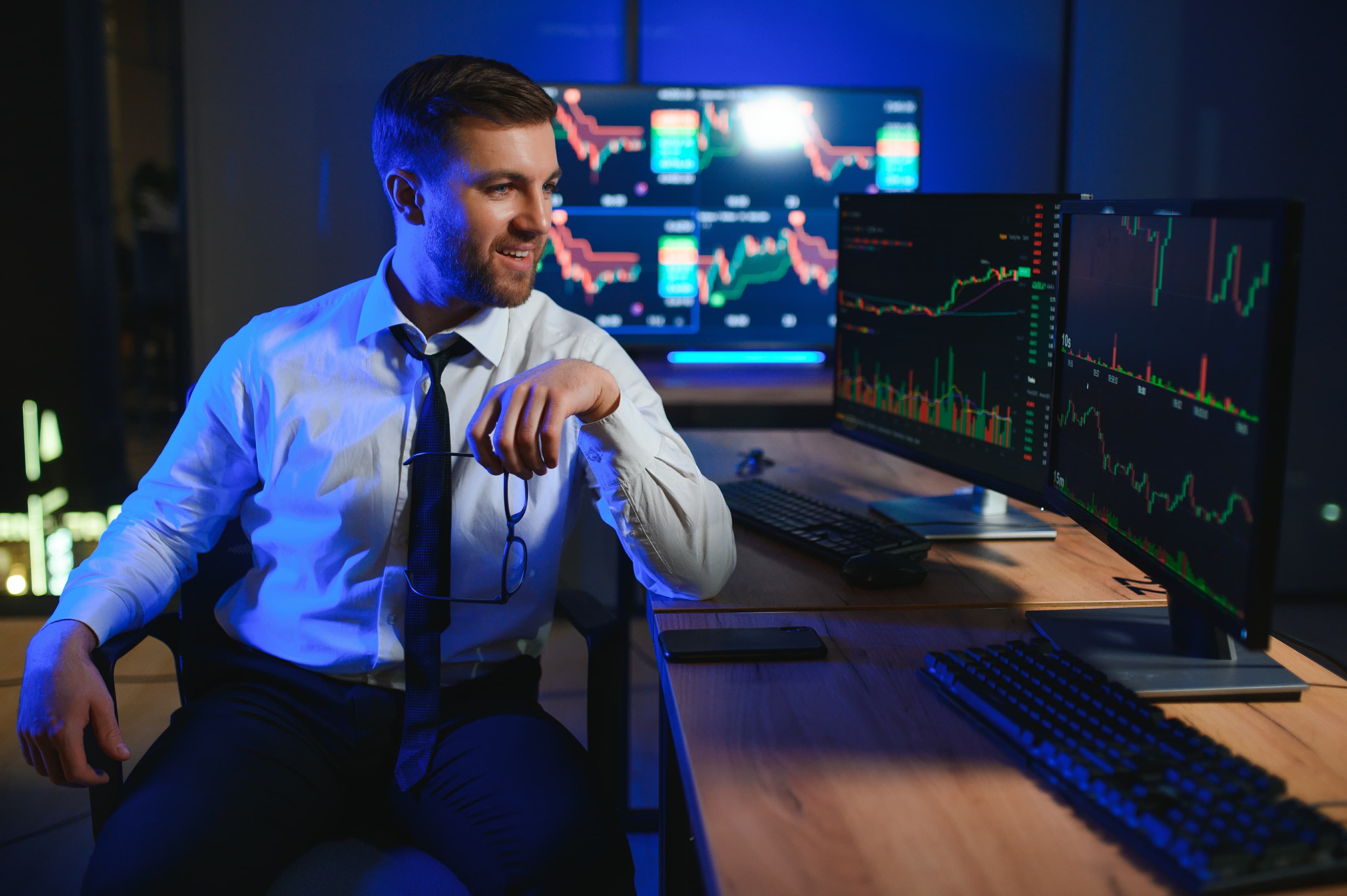Trader profesional con setup NinjaTrader en monitores azules llevando journal de trading de futuros para fondeo