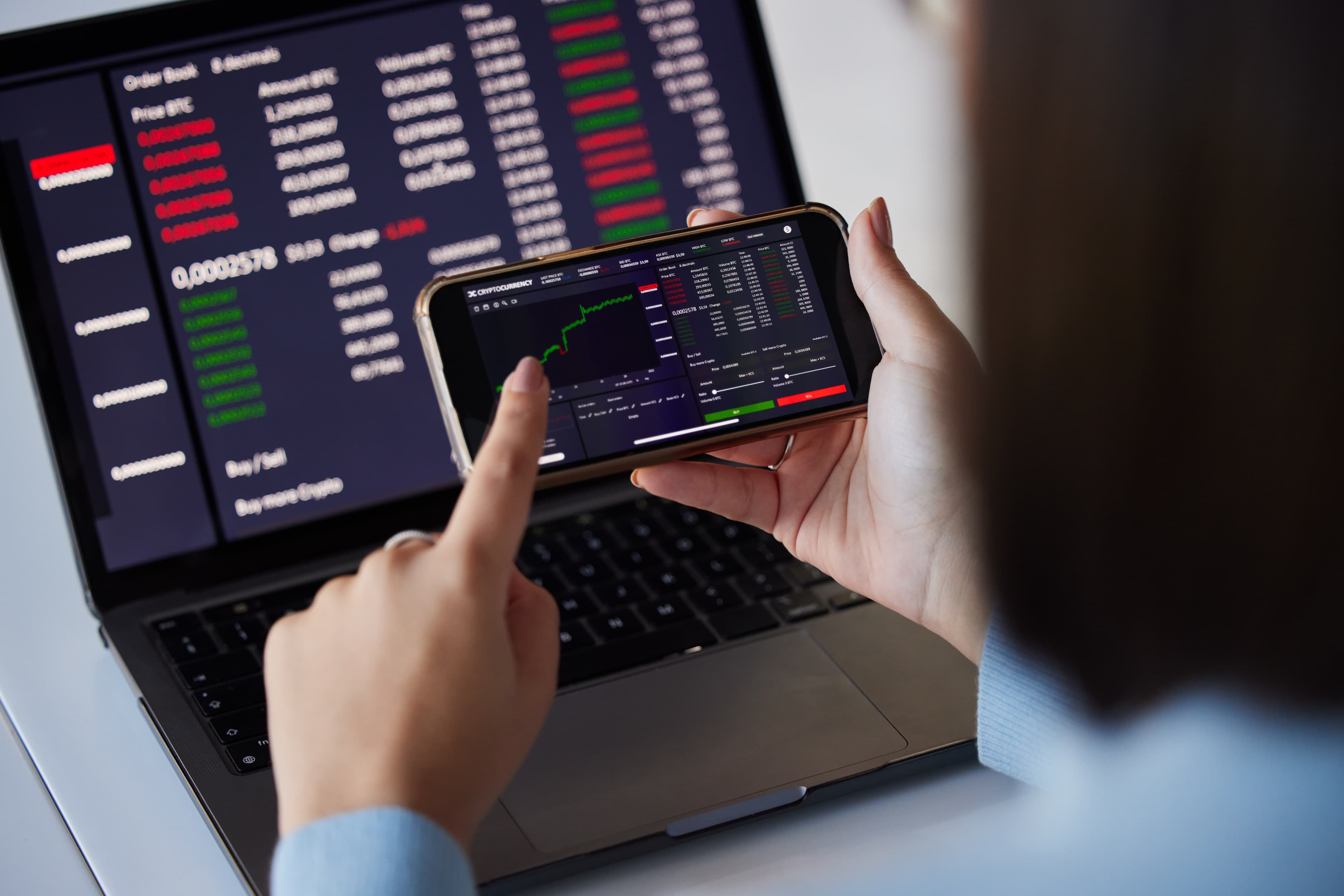 Trader revisando gráficas en laptop y móvil controlando emociones en trading de futuros para pasar prueba de fondeo